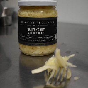 jar of sauerkraut and a fork with some sauerkraut in foreground