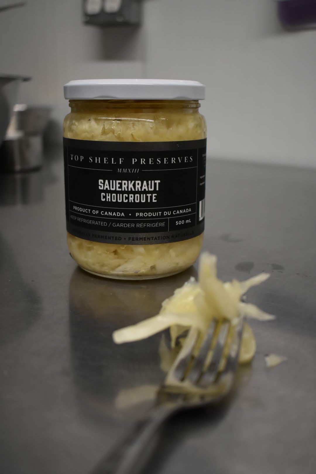 jar of sauerkraut and a fork with some sauerkraut in foreground