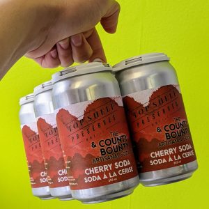 six cans of soda with a red label on a neon green background